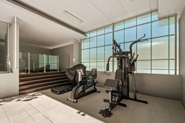 Un gimnasio moderno con máquinas de cardio, una banca y una escaladora.
