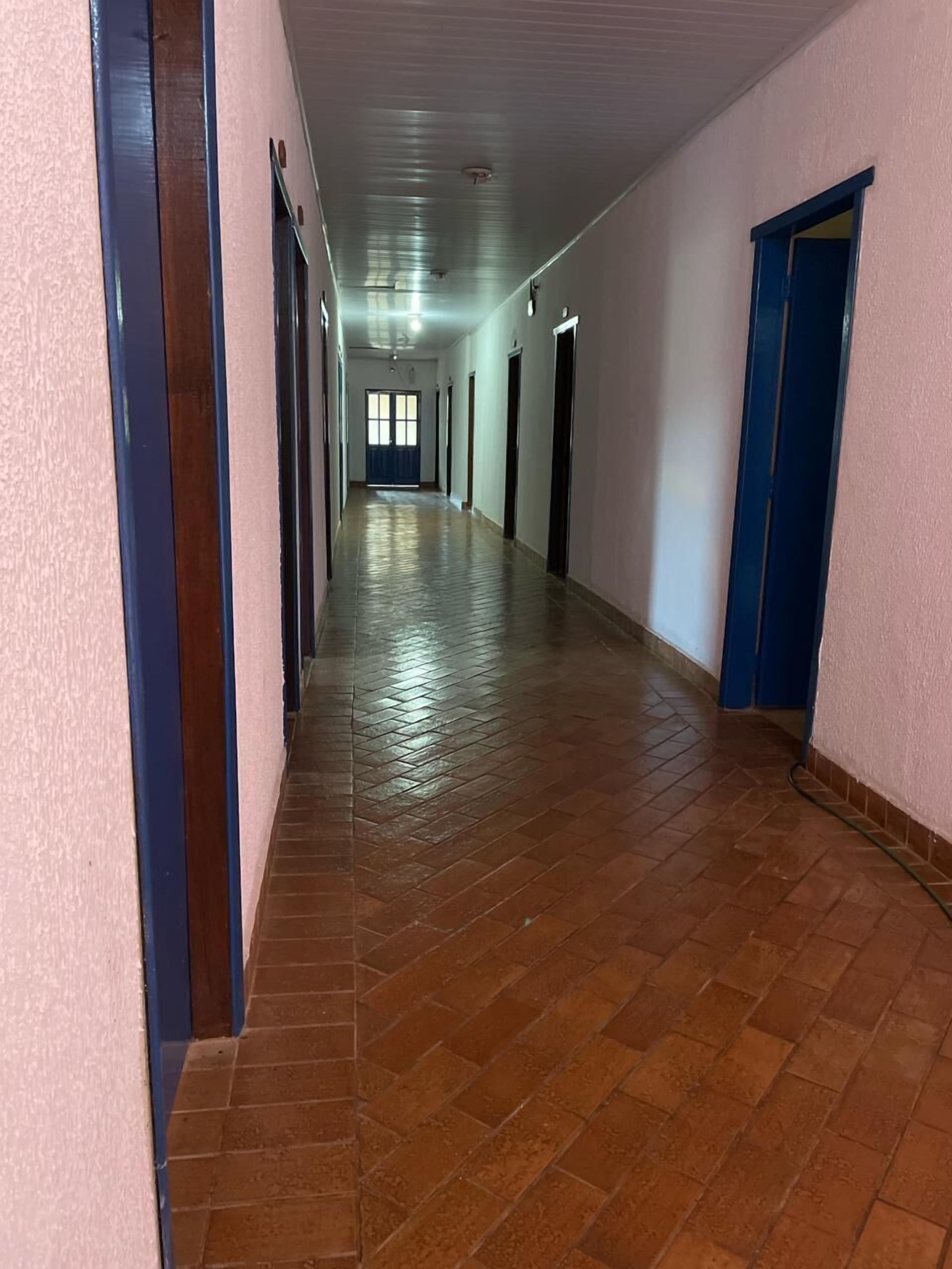A long, narrow hallway with tiled flooring and doors on both sides.