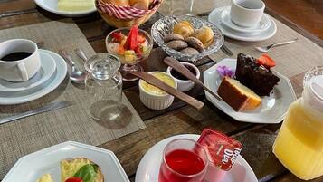 Una mesa dispuesta con diversos alimentos para el desayuno, como bollería, frutas y bebidas.