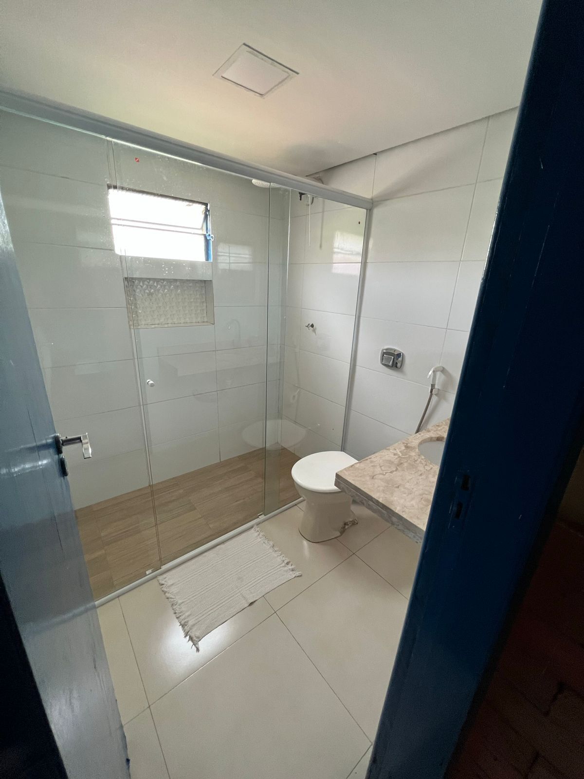 Un baño moderno con cabina de ducha de vidrio, inodoro y encimera de mármol.