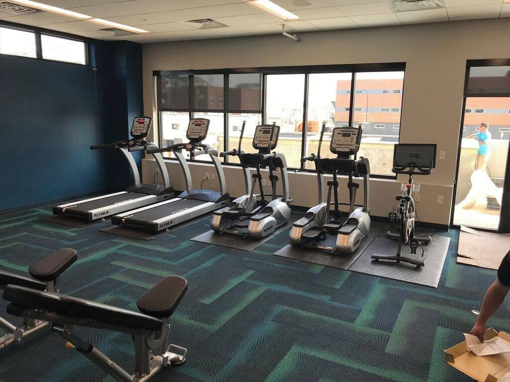 A gym with treadmills, elliptical machines, and a bench press area.