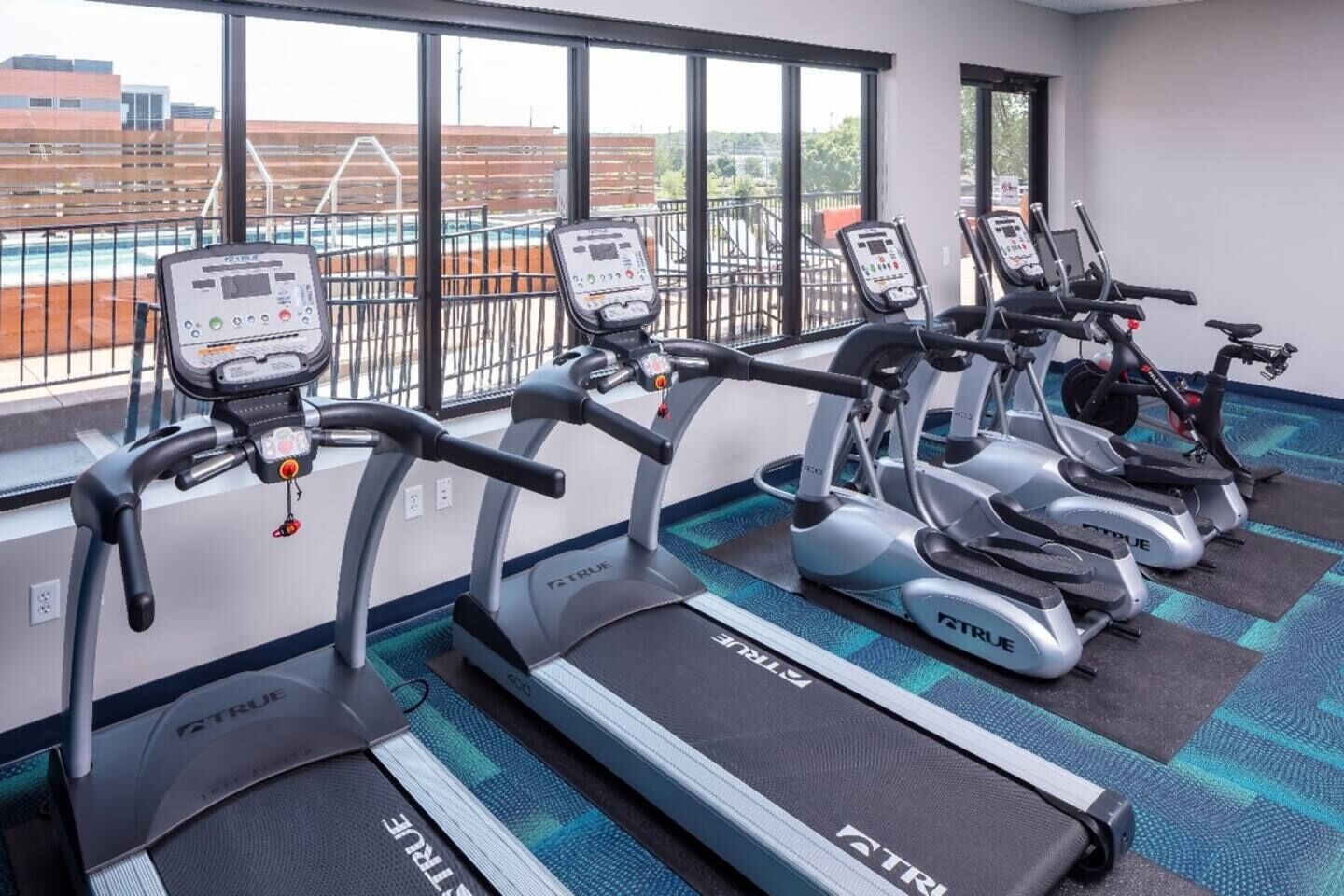 A gym with multiple treadmills arranged in a row, each with a digital display and control panel.
