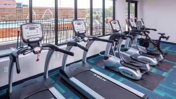 A gym with multiple treadmills arranged in a row, each with a digital display and control panel.