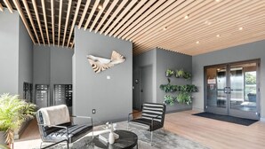 Un vestíbulo moderno con techo de madera, una gran escultura abstracta y un área de estar con una mesa de centro.