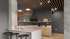 A modern kitchen with a central island, bar stools, pendant lighting, and holiday decorations. - NashVybe PH Condo| Broadway & Gulch| Pool, Parking (Nashville)