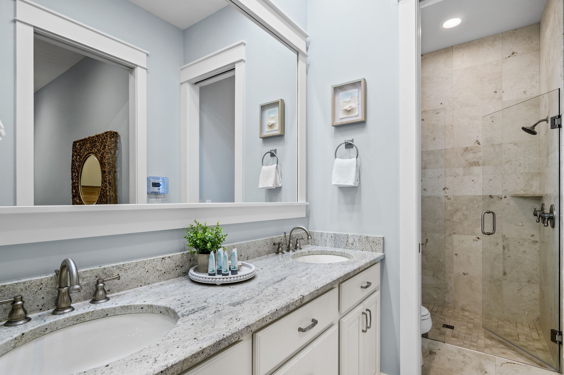 A bathroom with two sinks, a large mirror, and a shower area.