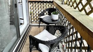 Un espacio al aire libre techado con mobiliario de mimbre, una mesa pequeña y una planta en maceta.
