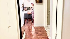 Un pasillo con suelo de espiga, paredes blancas y una escalera que conduce a otra habitación.