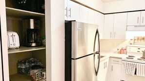 Una cocina con armarios blancos, un refrigerador de acero inoxidable, una cafetera y un tostador.
