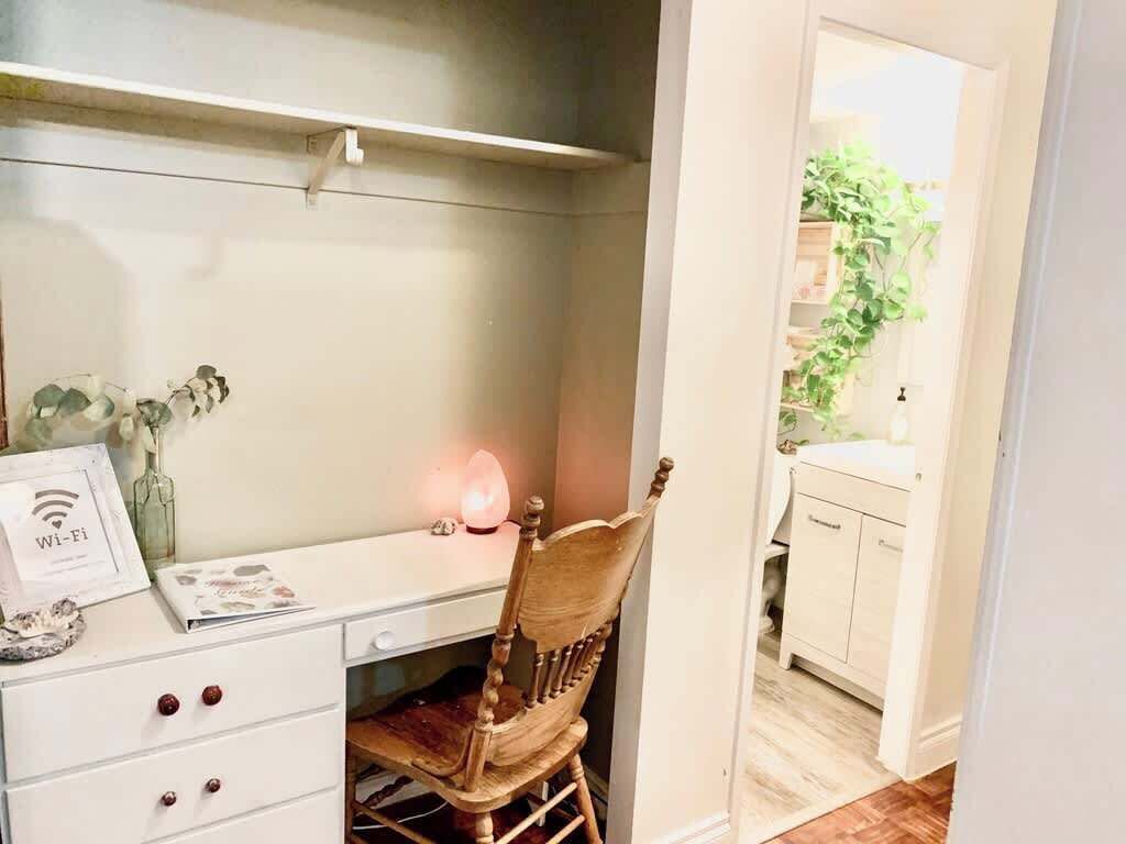 A white desk with a chair, a framed Wi-Fi symbol, and a pink lamp.