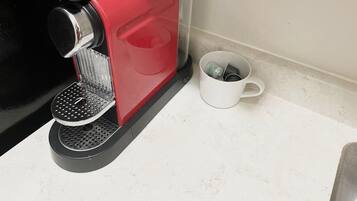 A red coffee machine with a transparent water container and a white mug on a countertop.