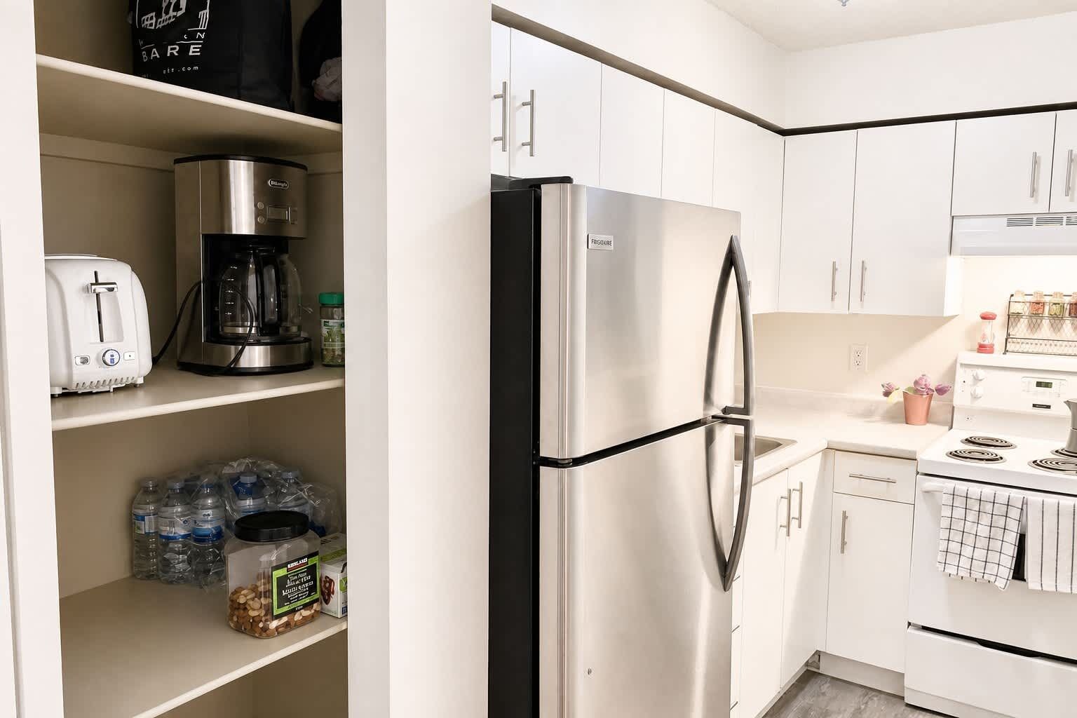 Una cocina moderna con un refrigerador de acero inoxidable, una cafetera y un tostador sobre la encimera.