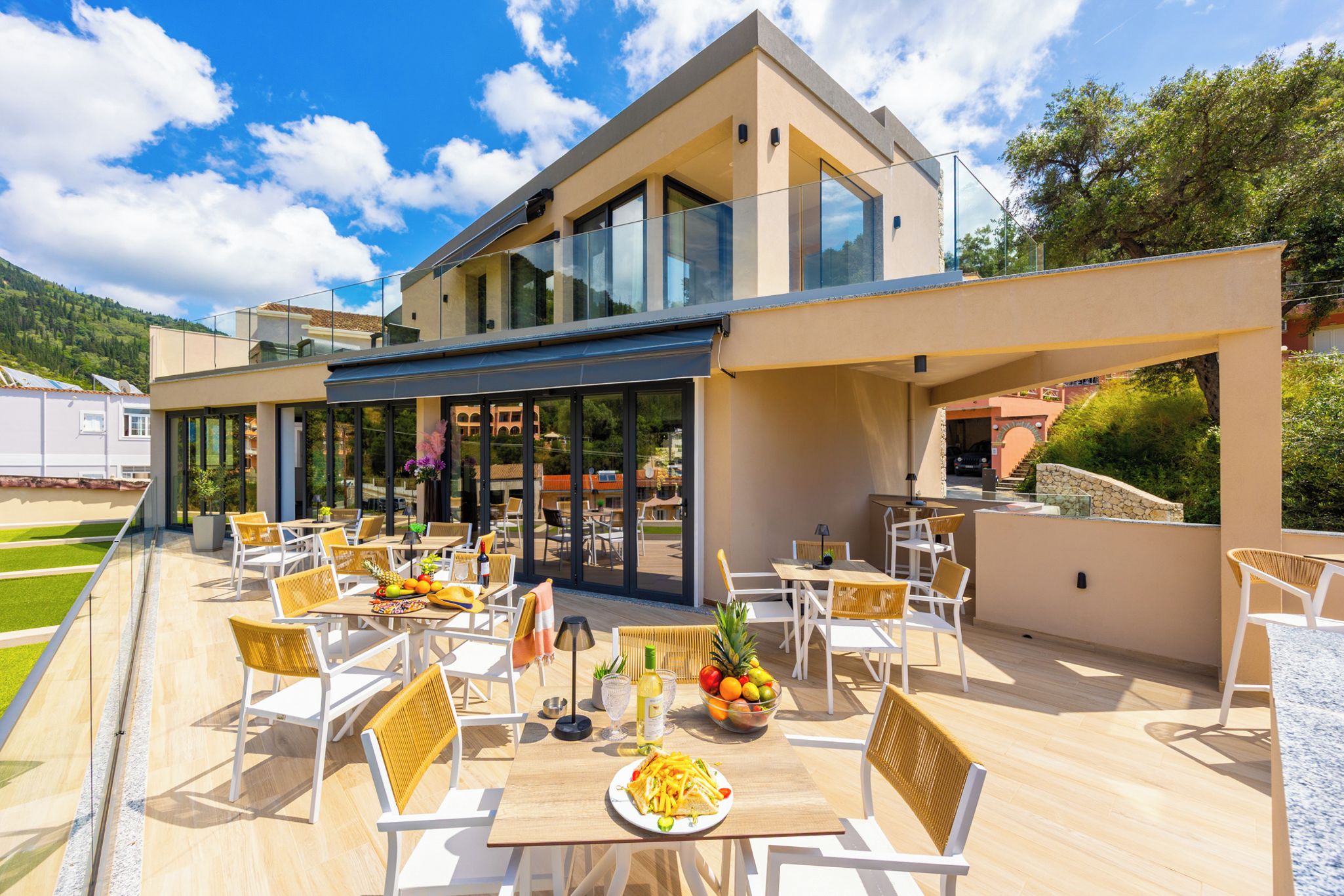 Un espace de restauration extérieur moderne, doté de tables et de chaises, d’une partie fermée par des parois de verre et offrant une vue sur le paysage environnant.