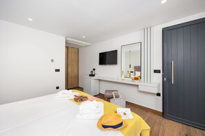 A modern hotel room with a large bed, a desk with a flat-screen TV, a mirror, and a dark-colored wardrobe. - Nobile Hotel (Corfu)