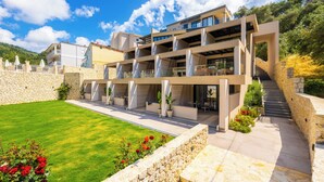 A modern multi-story building with a stone facade, a well-maintained lawn, and a staircase leading to the upper levels. - Nobile Hotel (Corfu)