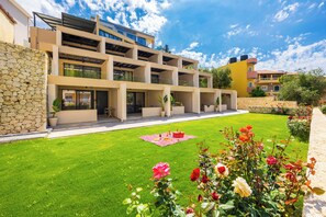 A modern multi-story building with balconies and a well-maintained lawn with flowers. - Nobile Hotel (Corfu)