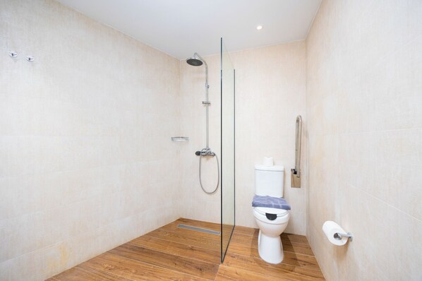 A modern bathroom with a glass shower enclosure, a toilet, and a wooden floor. - Nobile Hotel (Corfu)
