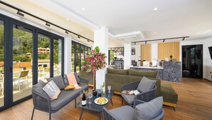 A spacious living area with a sofa, chairs, a dining table, and a view of a balcony. - Nobile Hotel (Corfu)