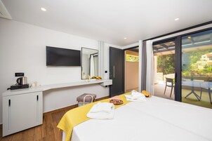 Una habitación de hotel moderna con una cama, un escritorio con televisor de pantalla plana, un armario y una puerta corrediza de vidrio que da a un patio exterior.
