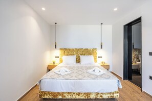 A modern hotel room with a large bed, wooden flooring, and a gold-patterned headboard. - Nobile Hotel (Corfu)