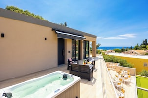 Una terraza moderna al aire libre con jacuzzi, zona de estar y vistas al mar.
