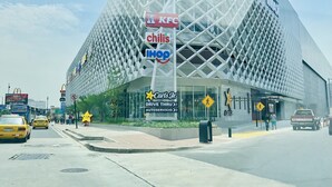 A modern IMAX theater with a unique geometric facade, surrounded by various commercial establishments.