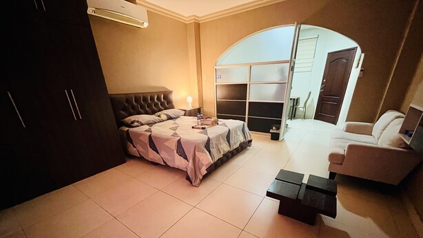 A bedroom with a bed, a desk, a chair, and a wardrobe.