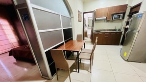 A compact kitchen with a dining table and chairs, a microwave, and a refrigerator.