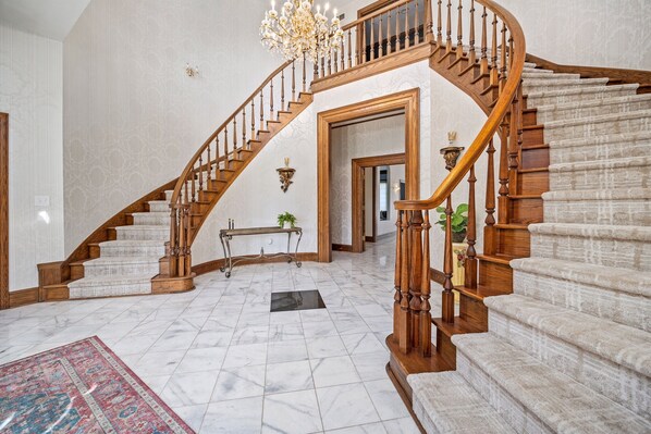 A grand staircase with a wooden finish, marble flooring, and a chandelier. - 12,000 Sq Ft Luxury Mansion | Events & Weddings (Medina)