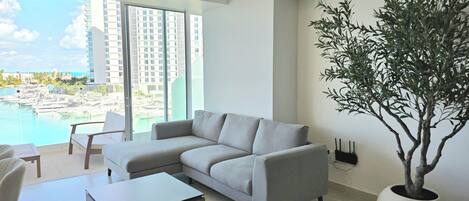 A modern living room with a grey sofa, a coffee table, and a large potted plant.