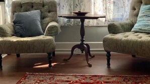 Una habitación con dos sillones, una mesita y un tapete estampado.