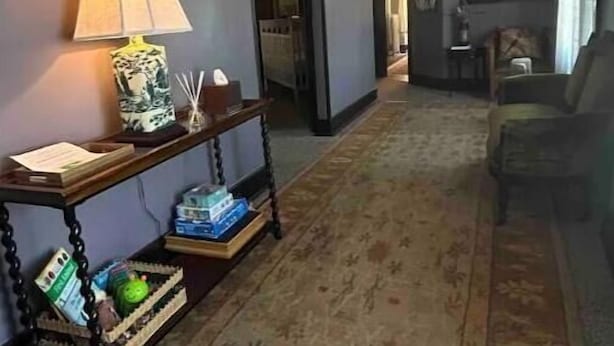 Un couloir avec une lampe, une console et un tapis à motifs.