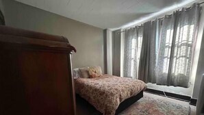 Une chambre à coucher avec un lit, une fenêtre avec des rideaux et un tapis.
