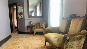 Une pièce avec un tapis à motifs, une chaise en bois, un canapé et un miroir au mur.