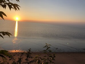 Una spiaggia al tramonto, con palme sullo sfondo e cielo sereno.