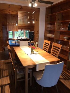 Un interno in legno con un tavolo da pranzo, sedie, un vaso con fiori e una libreria.