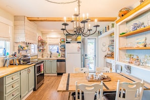 Une cuisine avec des meubles de rangement en bois, un îlot central, un lustre et divers appareils électroménagers.