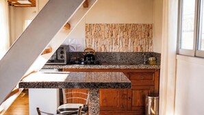 A kitchen with a granite countertop, wooden cabinets, a stainless steel sink, and a built-in wood wall panel. - Recanto das Águas - Urubici - SC (Urubici)