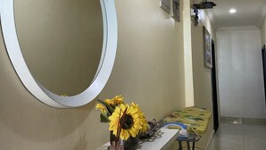 A hallway with a white reception desk, a large mirror, and a vase with sunflowers. - NUMBER ELEVEN APARTMENTS (Lagos)