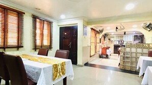A dining area with tables set for service, a kitchen area visible through a glass partition, and a ceiling fan. - NUMBER ELEVEN APARTMENTS (Lagos)