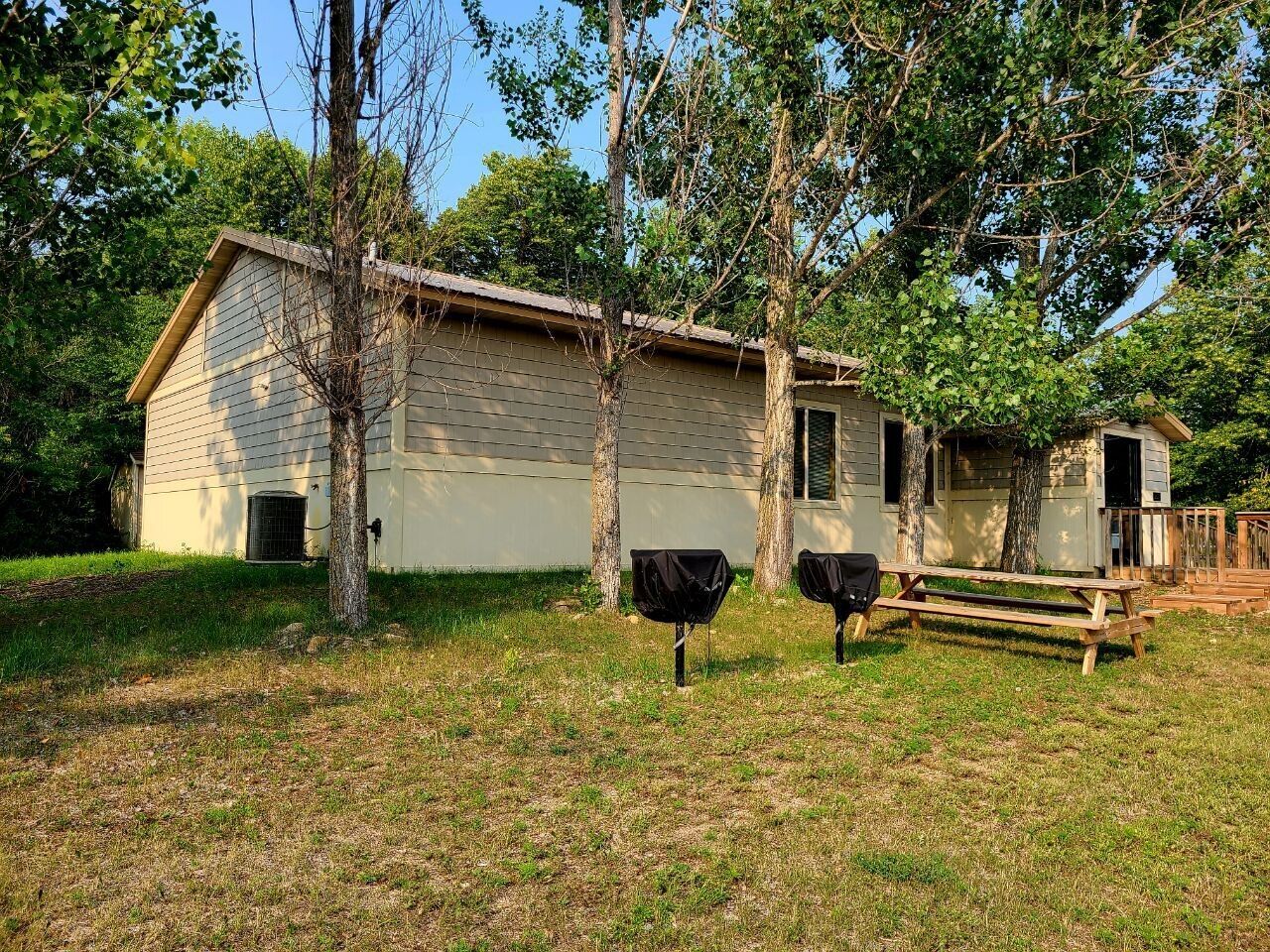 A single-story building with a sloped roof, surrounded by trees and grass.