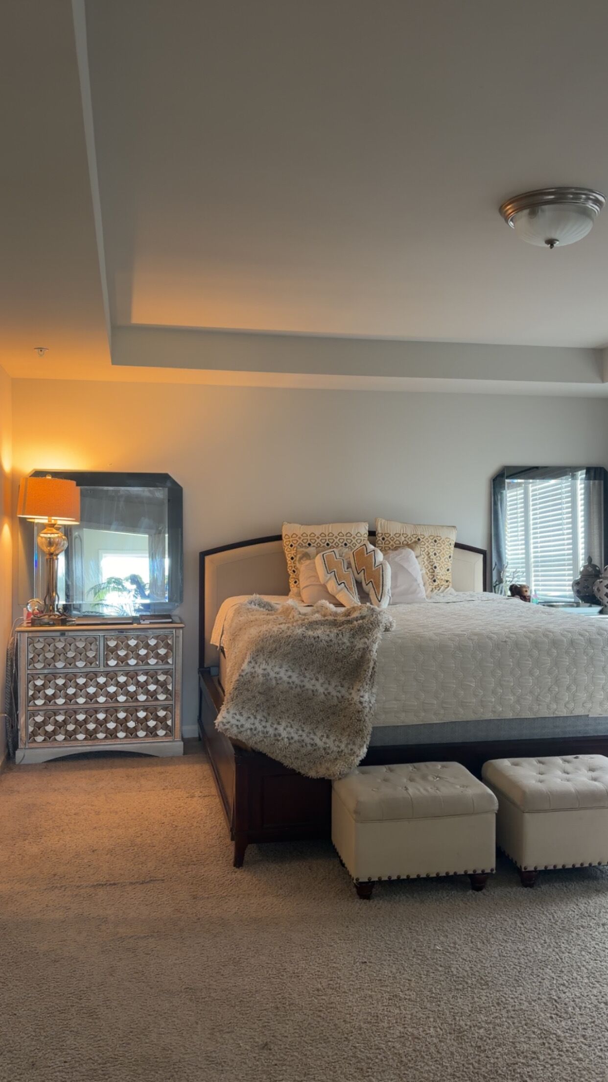 Un dormitorio con cama, mesita de noche, lámpara y ventana.