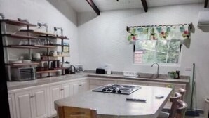 Een keuken met witte kasten, een centraal eiland en een plafondventilator.