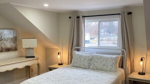 Une chambre à coucher avec un lit, des tables de chevet, un bureau et une fenêtre.