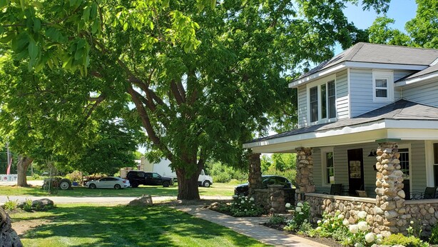 Une maison à deux étages, avec des fondations en pierre, un porche abrité et une pelouse bien entretenue.