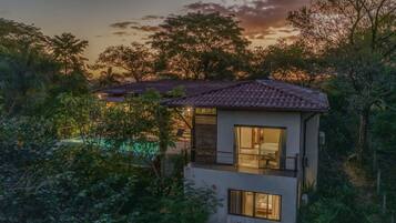 Enjoy a serene view of the lush garden and pool area from the large window in this villa's cozy bedroom.