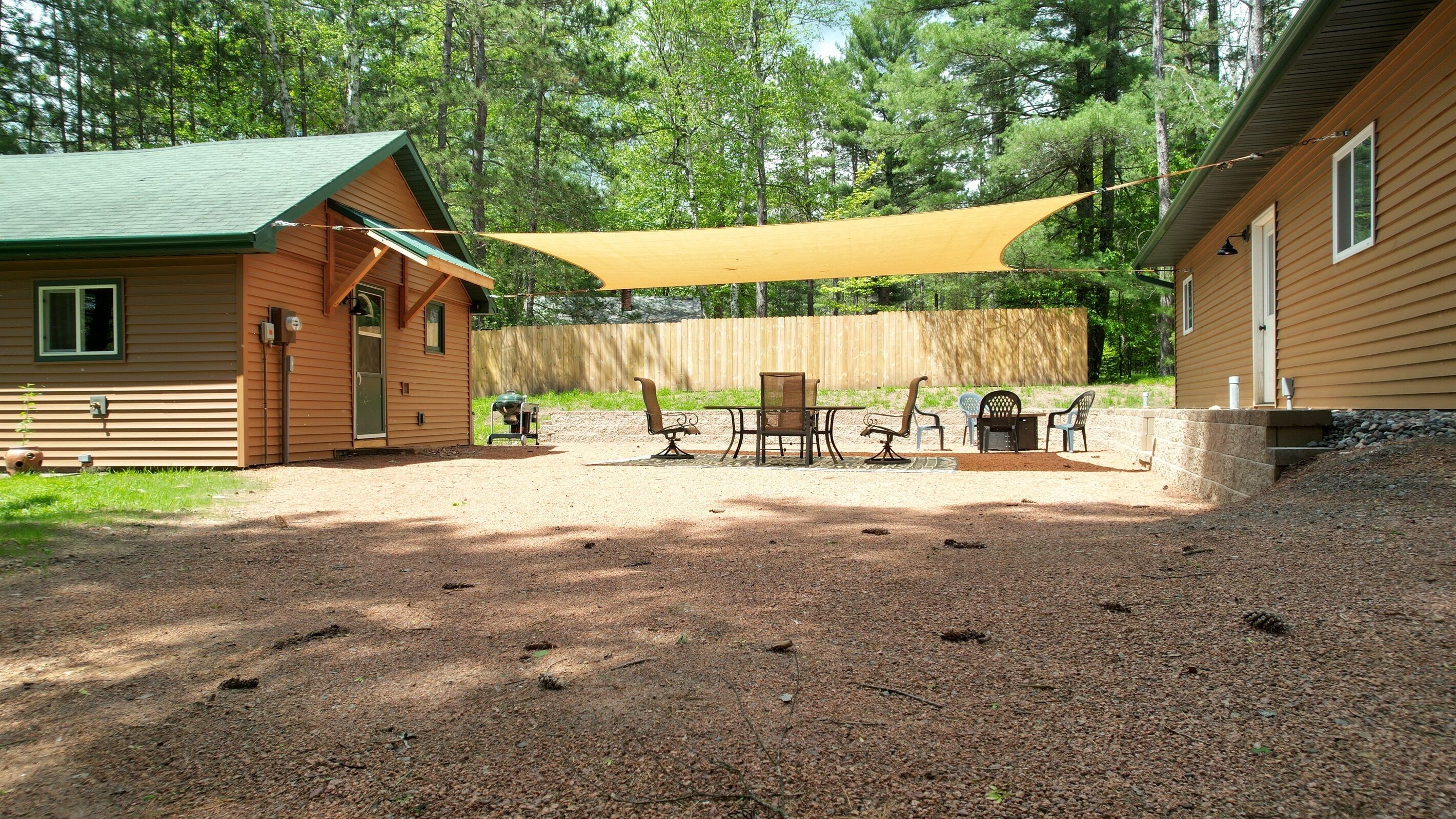 A cabin with a patio area featuring outdoor furniture and a shade sail.