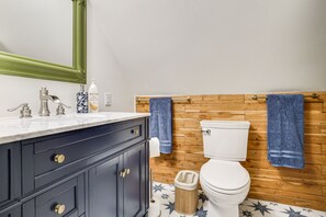 Ein Badezimmer mit einem hölzernen Waschtisch, einer weißen Toilette und einem blauen Handtuch, das an der Wand hängt.