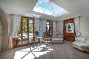Enjoy a bright and airy space with a glass dining table, comfortable sofa, and framed artwork.