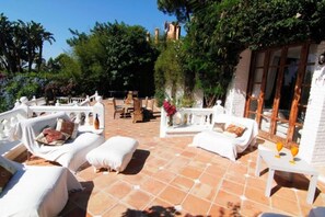 Relax in style with comfortable lounge chairs and a wooden table amidst lush greenery.
